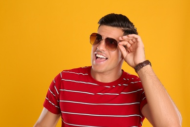 Handsome man wearing sunglasses on yellow background