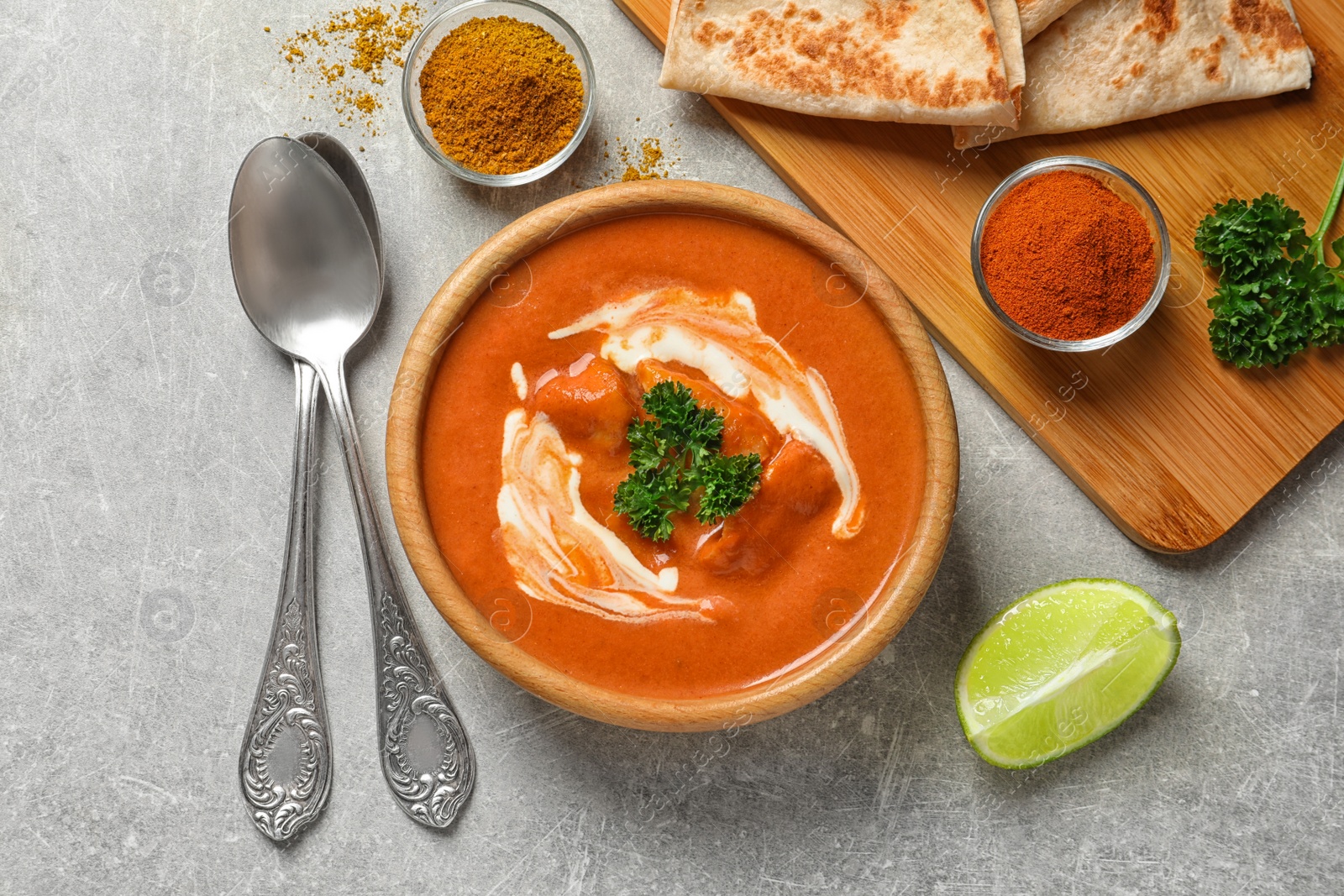 Photo of Delicious butter chicken served on grey table, flat lay. Traditional indian Murgh Makhani