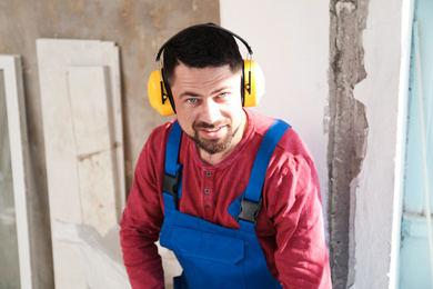 Handyman with protective headphones working indoors. Window installation