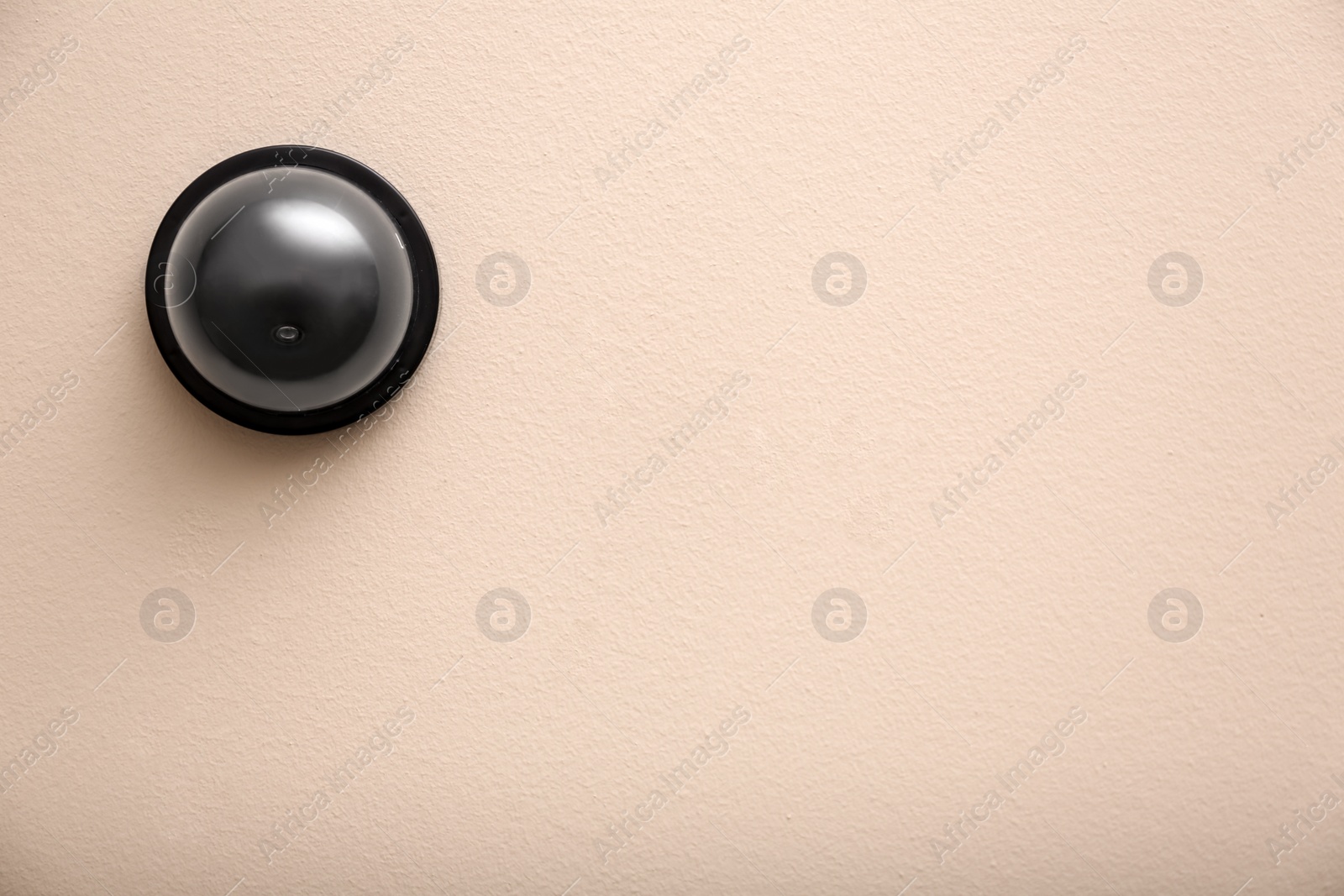 Photo of Modern CCTV security camera on beige wall. Space for text