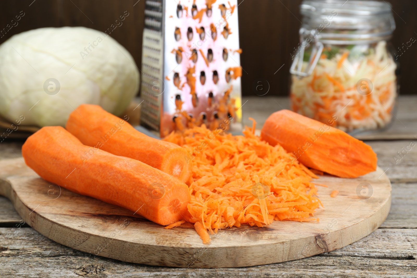 Photo of Cooking delicious sauerkraut soup. Fresh chopped carrot on wooden table, closeup