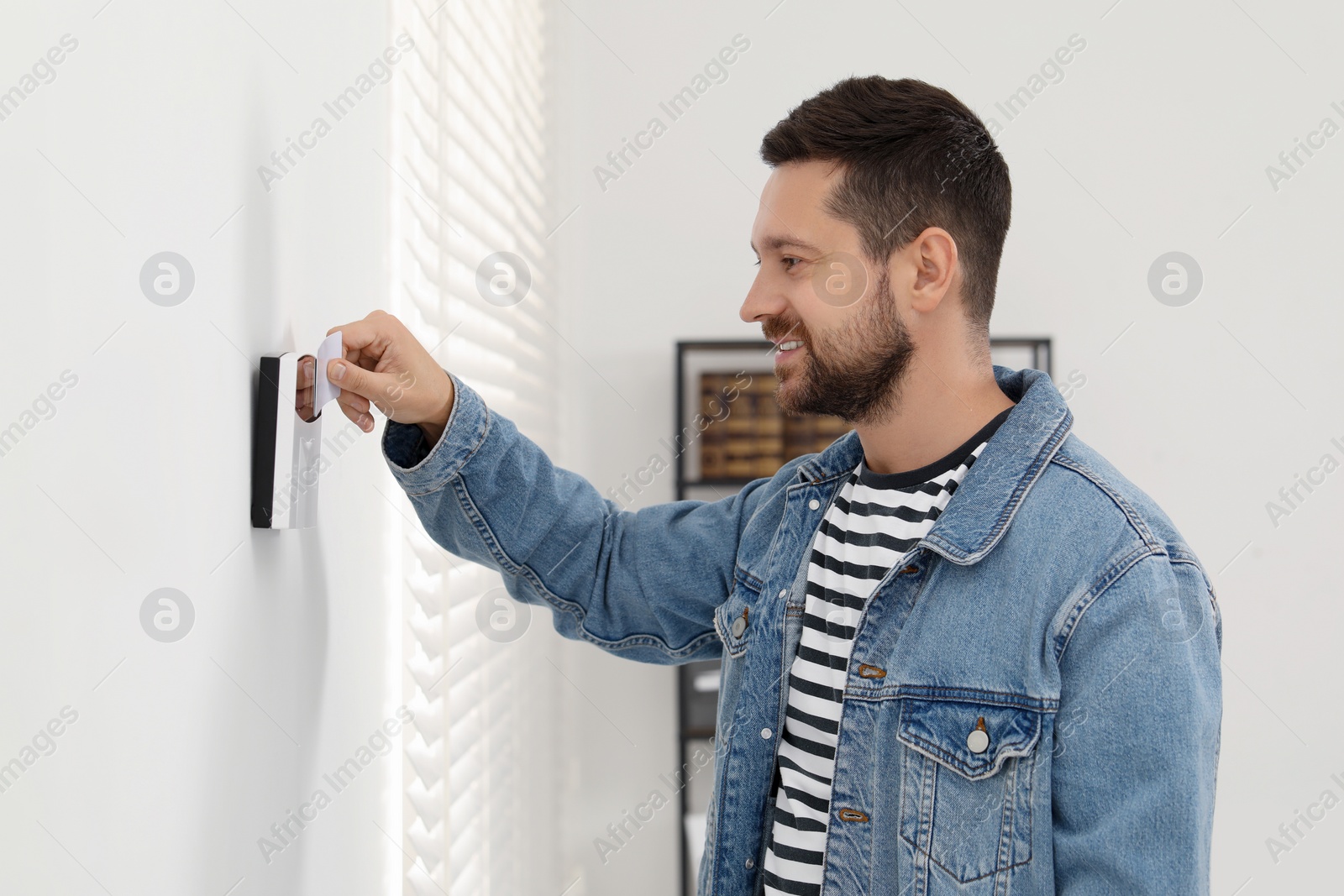 Photo of Home security system. Man using key card indoors