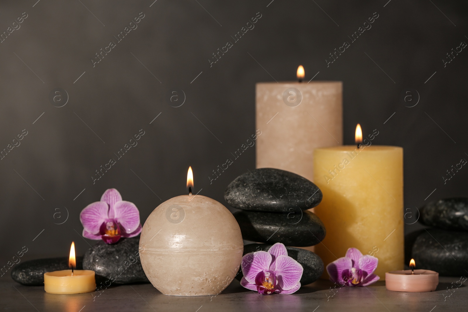 Photo of Composition with candles and spa stones on grey table