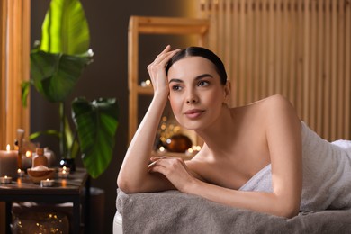 Spa therapy. Beautiful young woman lying on massage table in salon, space for text