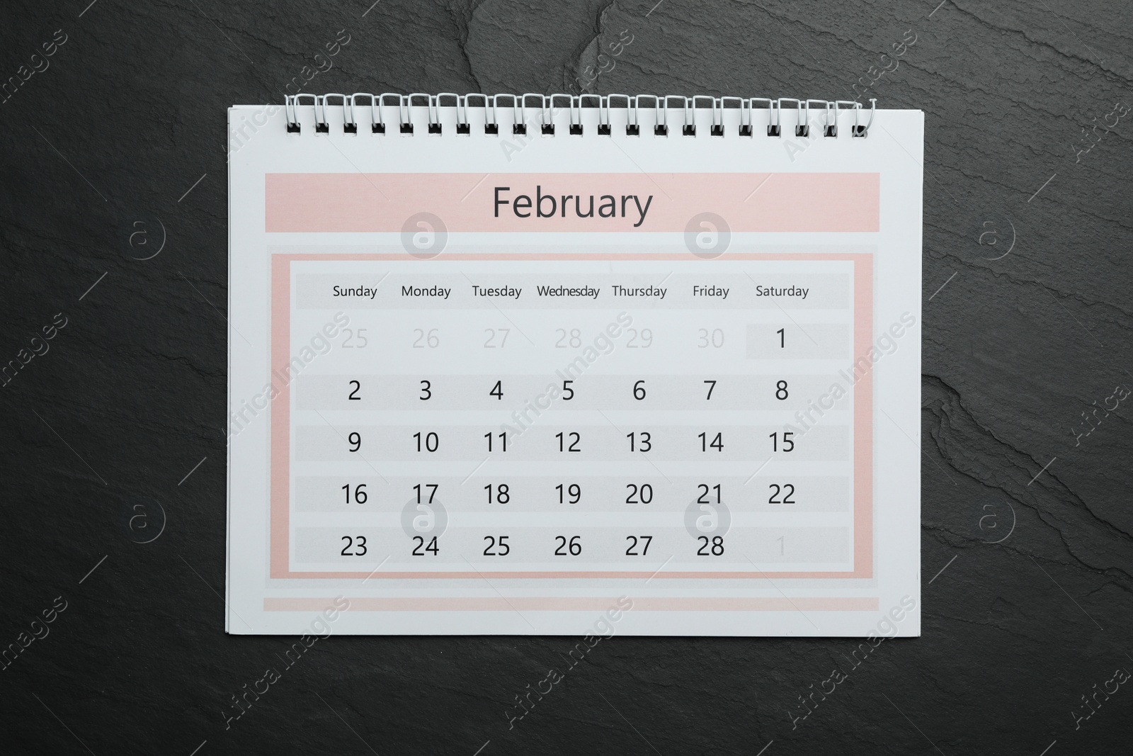 Photo of February calendar on black stone background, top view