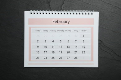 Photo of February calendar on black stone background, top view