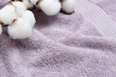 Cotton flowers on violet terry towel, closeup. Space for text