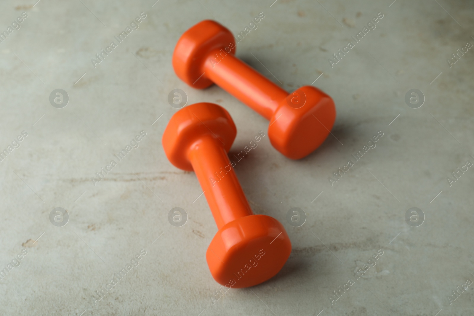 Photo of Orange vinyl dumbbells on light grey table