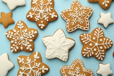 Photo of Tasty star shaped Christmas cookies with icing on light blue background, flat lay