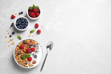 Photo of Healthy homemade granola with yogurt and berries served on light grey table, flat lay. Space for text