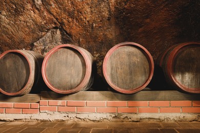 Photo of Many barrels of wine stored on shelf in cellar