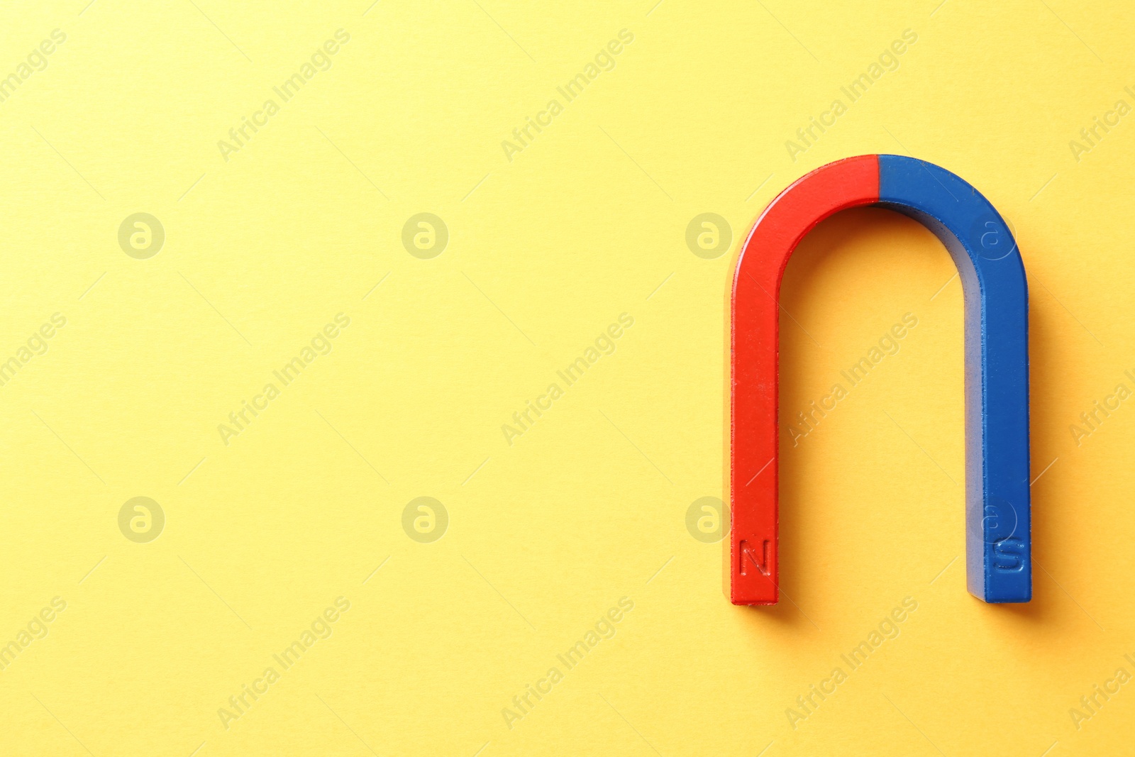 Photo of Red and blue horseshoe magnet on color background, top view with space for text