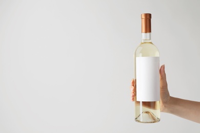 Woman holding bottle with delicious wine on white background