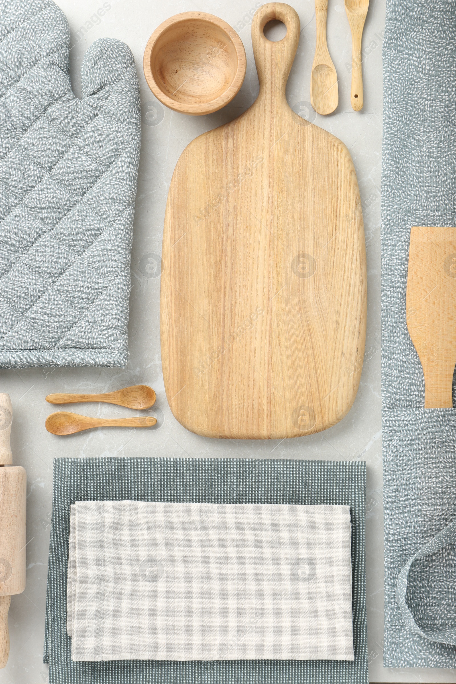 Photo of Kitchen napkins, apron and different utensils on light grey table, flat lay