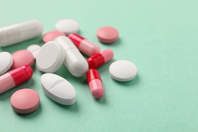 Photo of Pile of different pills on green background, closeup. Space for text