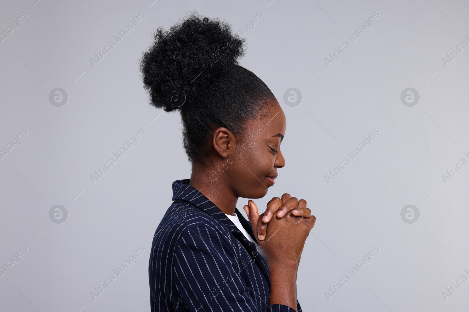 Photo of Woman with clasped hands praying to God on light grey background