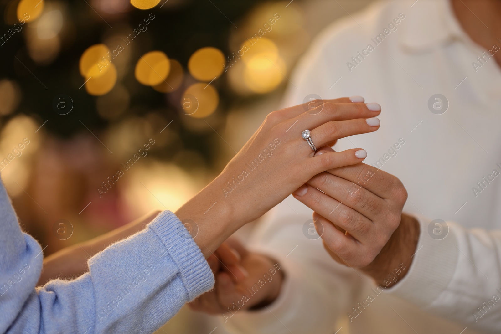 Photo of Making proposal. Man putting engagement ring on his girlfriend's finger against blurred lights, closeup