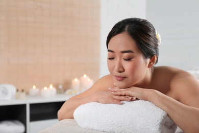 Photo of Beautiful Asian woman lying on massage table in spa salon. Space for text