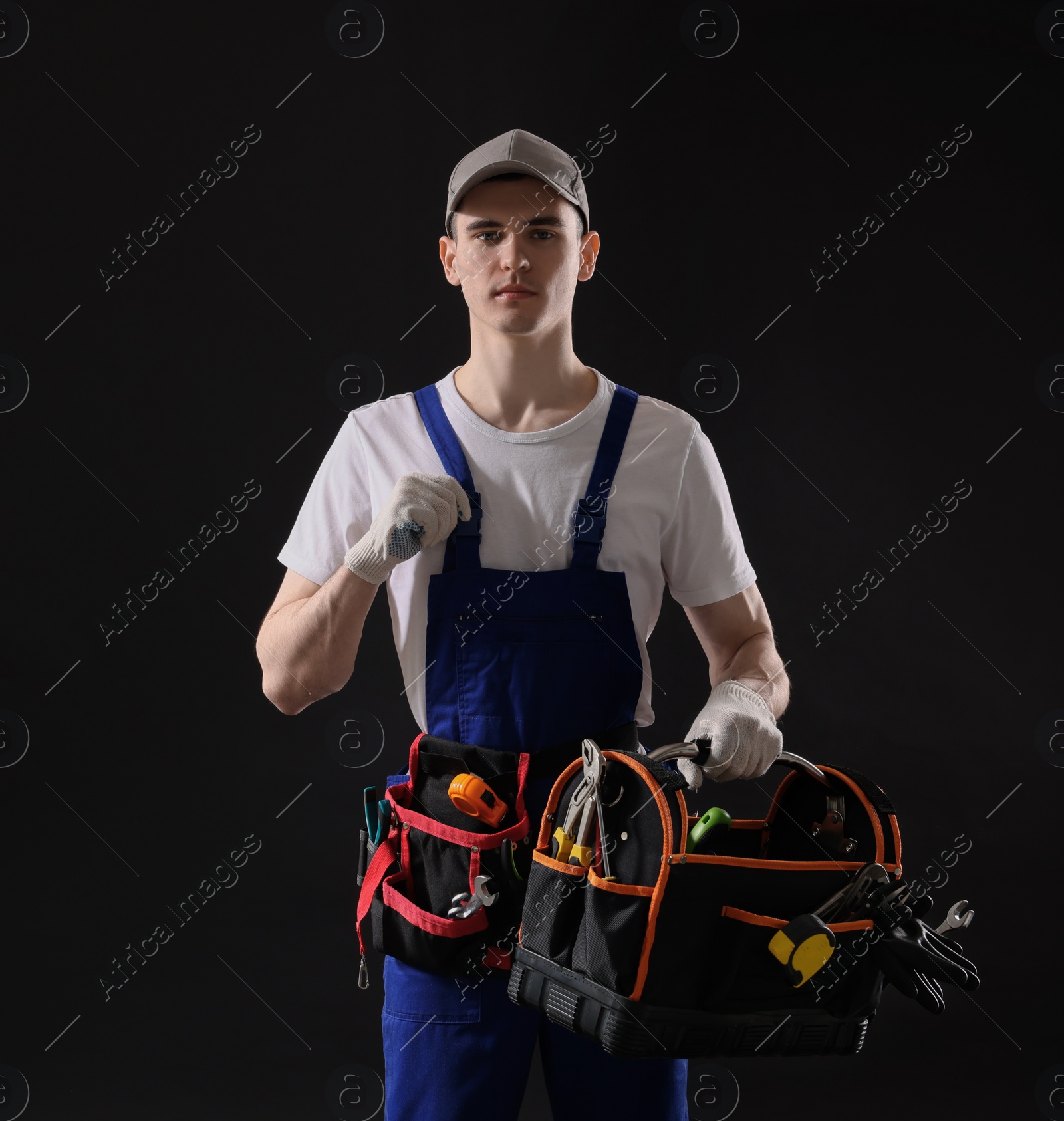 Photo of Professional repairman with tool box on black background