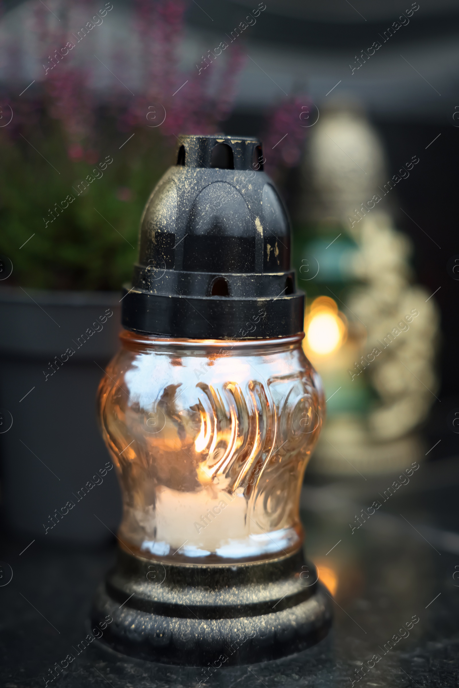 Photo of Grave light on granite surface at cemetery, closeup