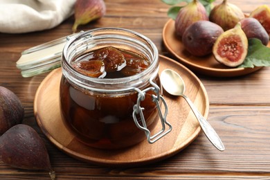 Jar of tasty sweet jam and fresh figs on wooden table