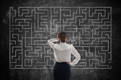 Businesswoman looking at chalkboard with illustration of maze