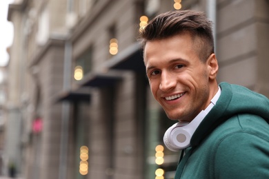 Photo of Portrait of handsome young man with headphones outdoors. Space for text