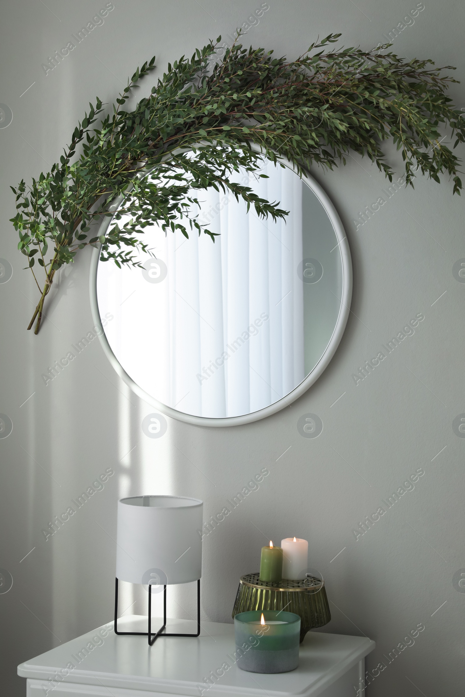 Photo of Stylish mirror decorated with green eucalyptus in room