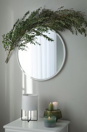 Stylish mirror decorated with green eucalyptus in room