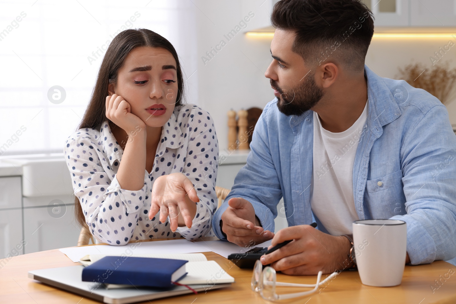 Photo of Young couple discussing family budget in kitchen