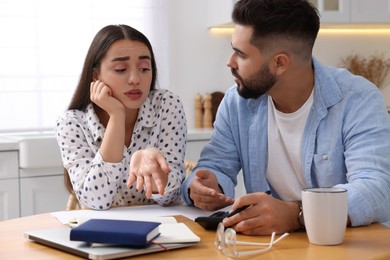 Young couple discussing family budget in kitchen