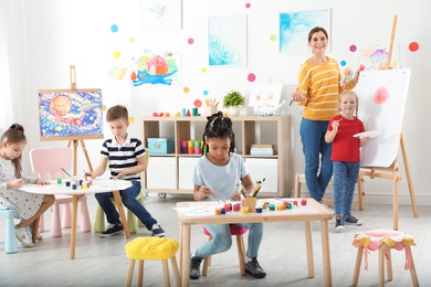 Photo of Children with female teacher at painting lesson indoors