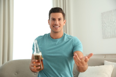 Photo of Man drinking beer while having online video conference at home, view from web camera. Social distancing during coronavirus pandemic