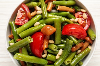 Photo of Delicious salad with green beans, mushrooms, pine nuts and tomatoes on white table, top view