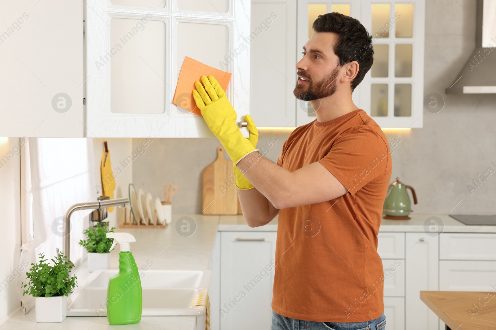 Photo of Spring cleaning. Man tidying up kitchen at home