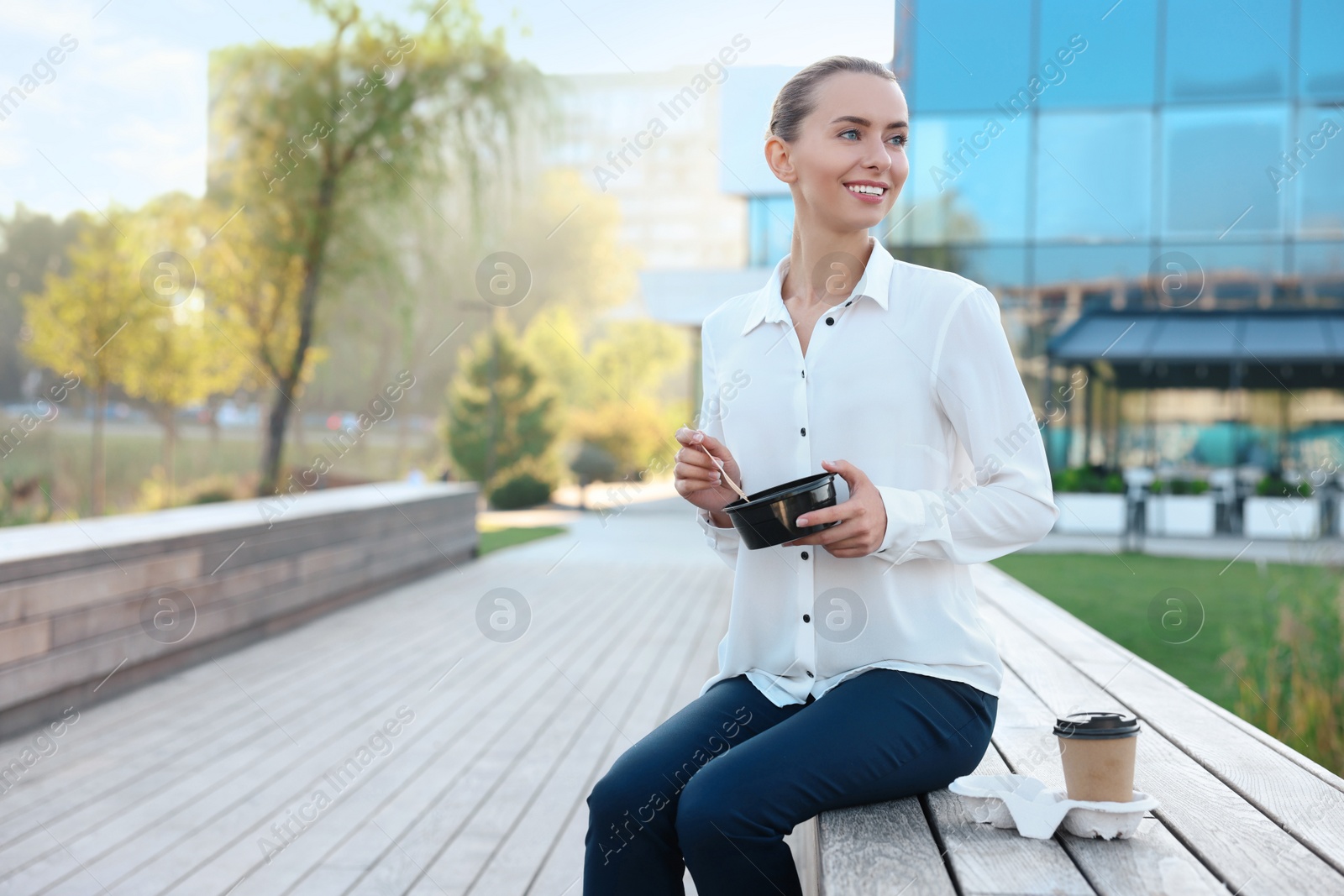 Photo of Smiling businesswoman with lunch box outdoors. Space for text