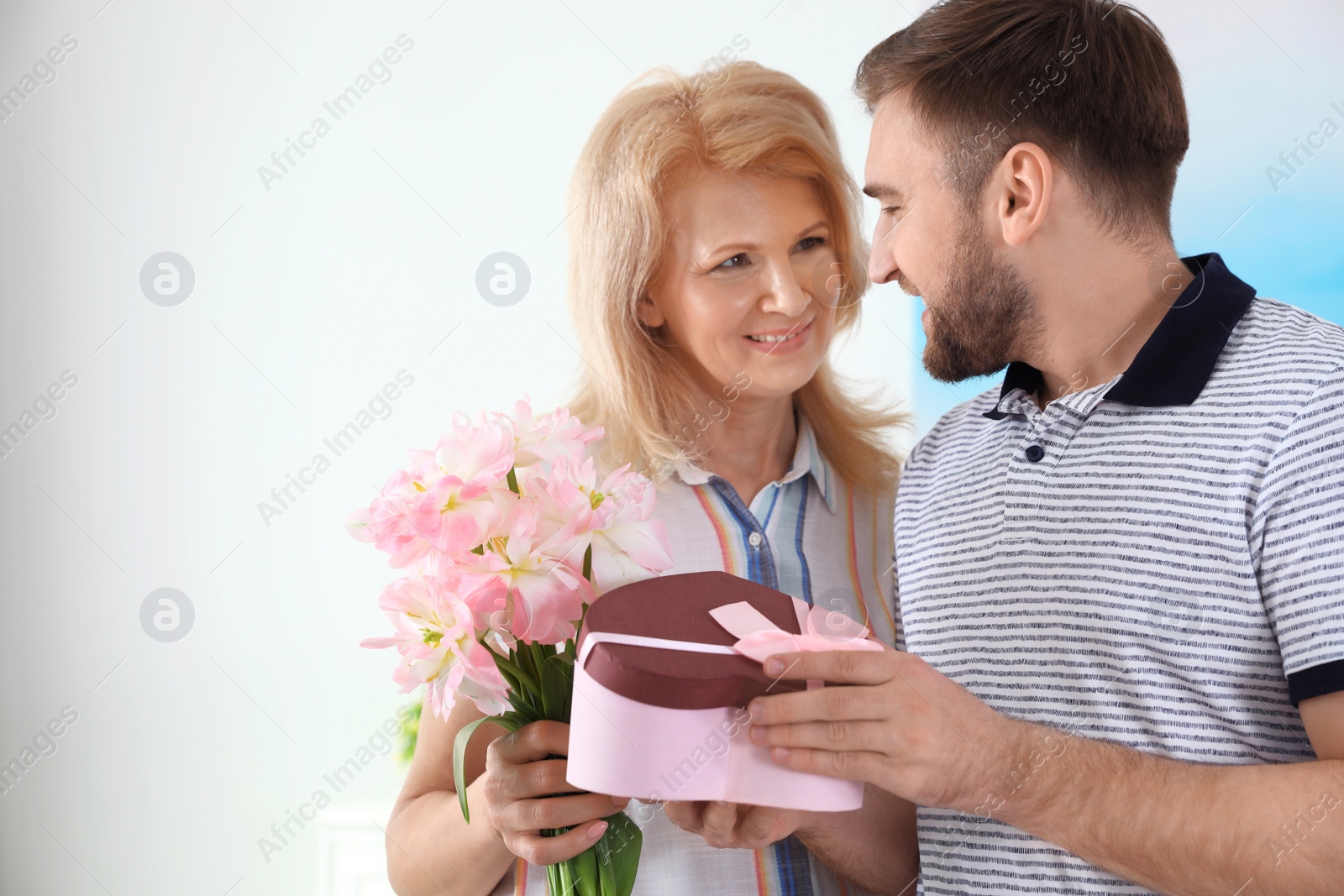 Photo of Young man congratulating his mature mom at home, space for text. Happy Mother's Day