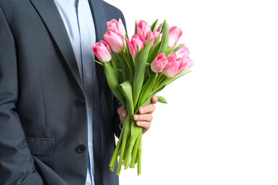 Photo of Man in elegant suit holding bouquet of beautiful spring tulips on light background, closeup. International Women's Day