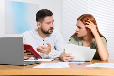 Photo of Couple calculating taxes at table in room