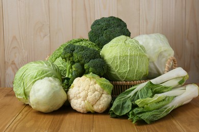 Photo of Many different types of fresh cabbage on wooden table