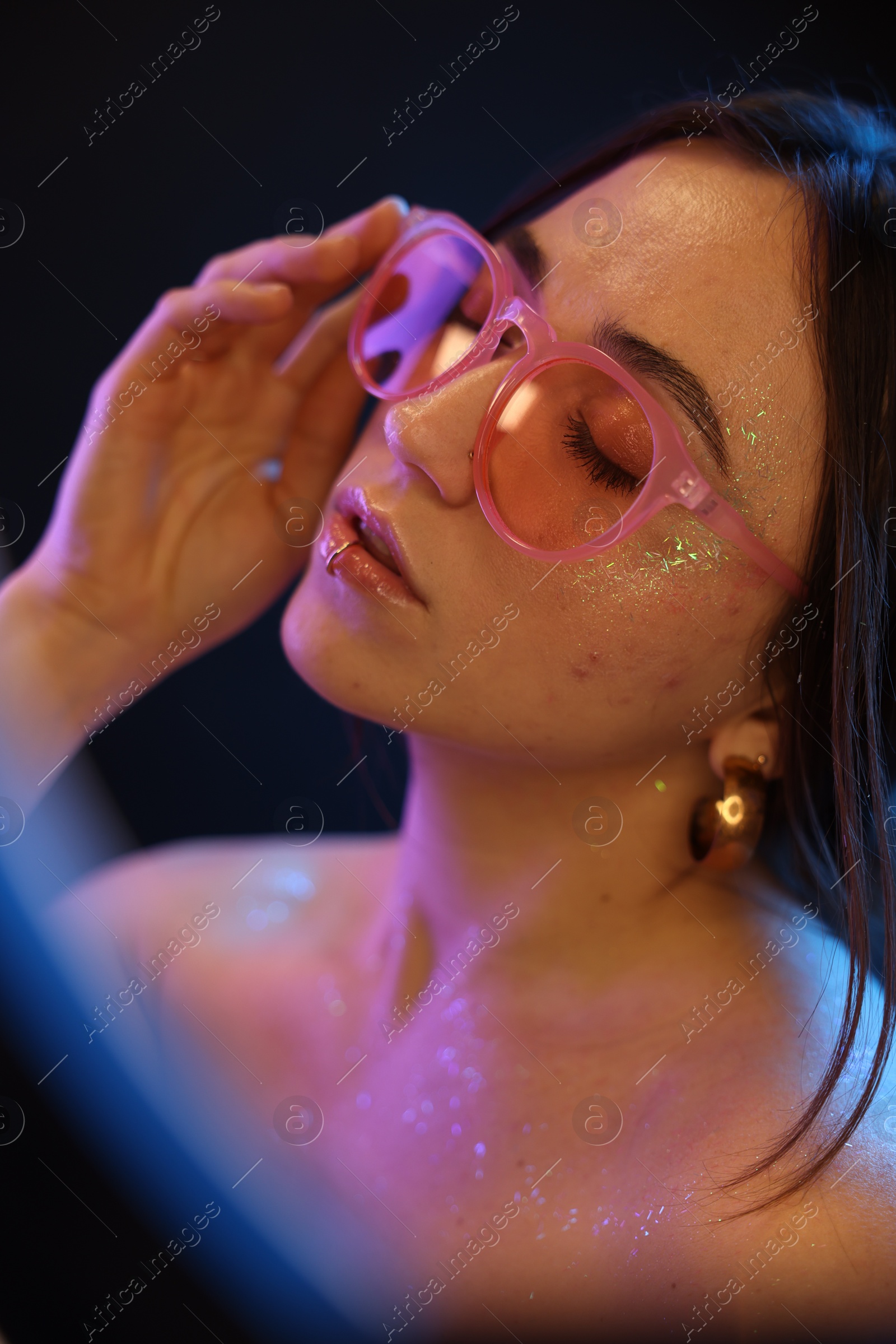 Photo of Beautiful woman in glasses on dark background in neon lights