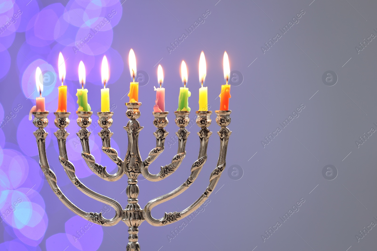 Photo of Hanukkah celebration. Menorah with burning candles on grey background with blurred lights, space for text