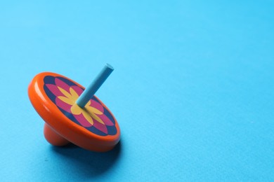 Photo of One colorful spinning top on light blue background, space for text