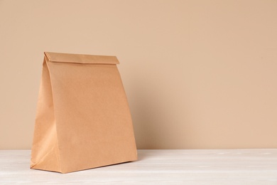 Photo of Paper bag on table against color background. Mockup for design