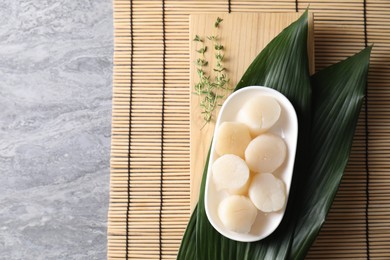 Fresh raw scallops, thyme and leaves on grey table, flat lay. Space for text