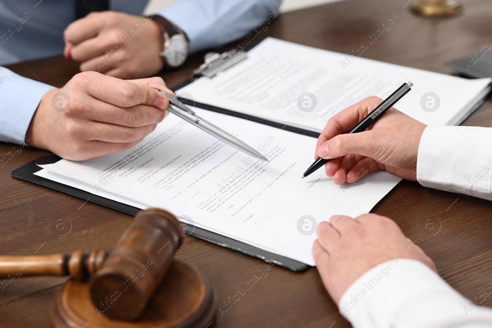 Photo of Lawyers working with documents at wooden table, closeup