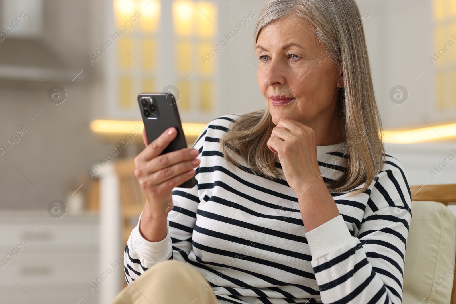 Photo of Senior woman using mobile phone at home