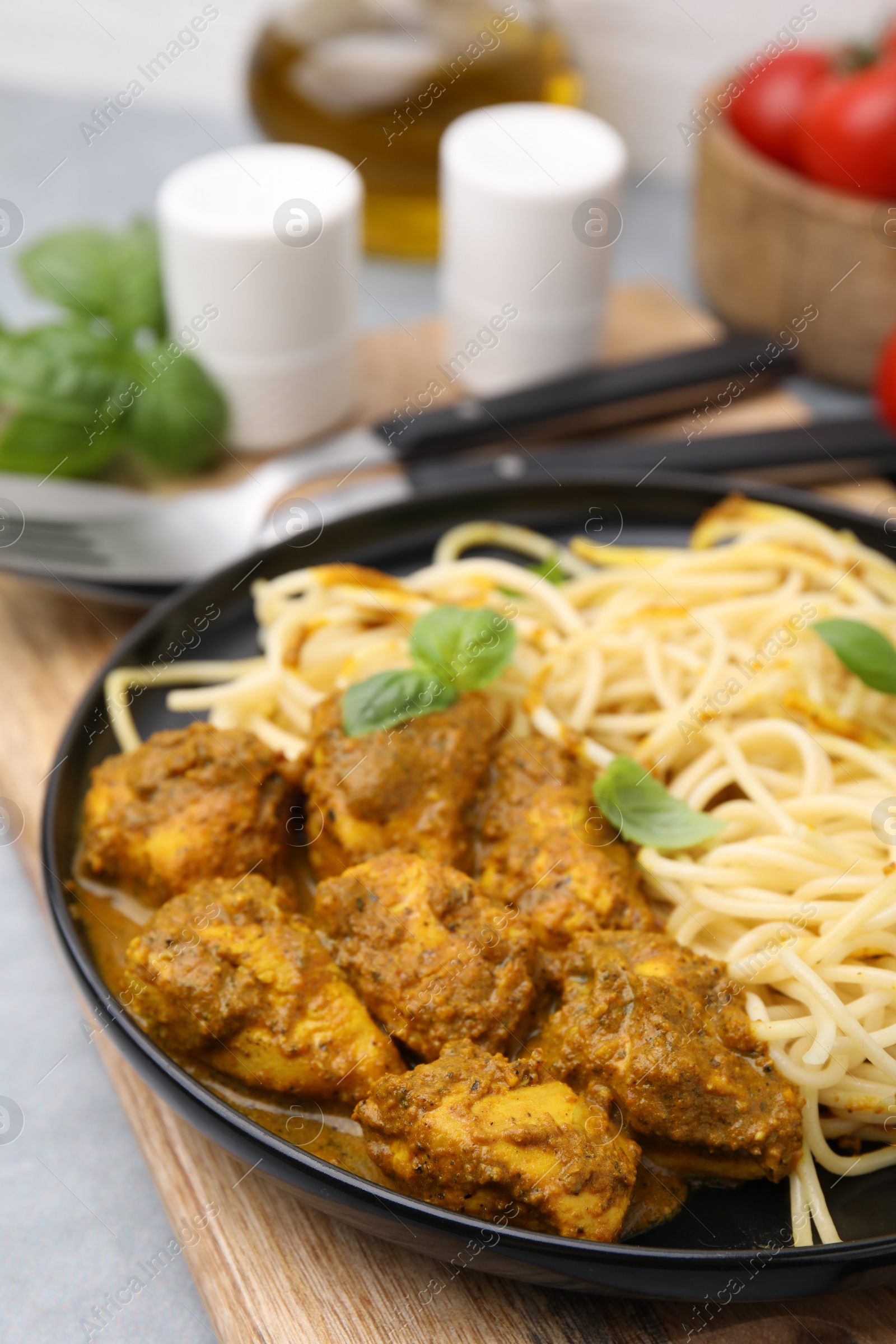 Photo of Delicious pasta and chicken with curry sauce served on table, closeup