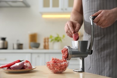 Photo of Man using hand meat grinder in kitchen, closeup