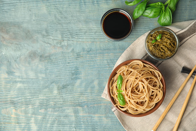 Photo of Tasty buckwheat noodles served on blue wooden table, flat lay. Space for text